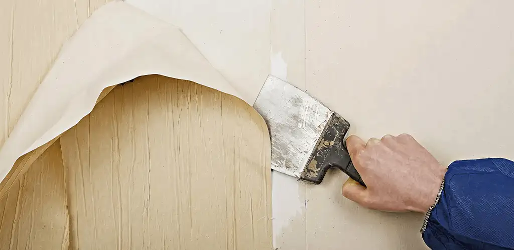 Handyman removing wallpaper with a scraper for wall preparation in Springfield, MO