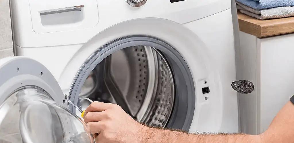Handyman repairing a front-load washing machine and inspecting the drum in Springfield, MO