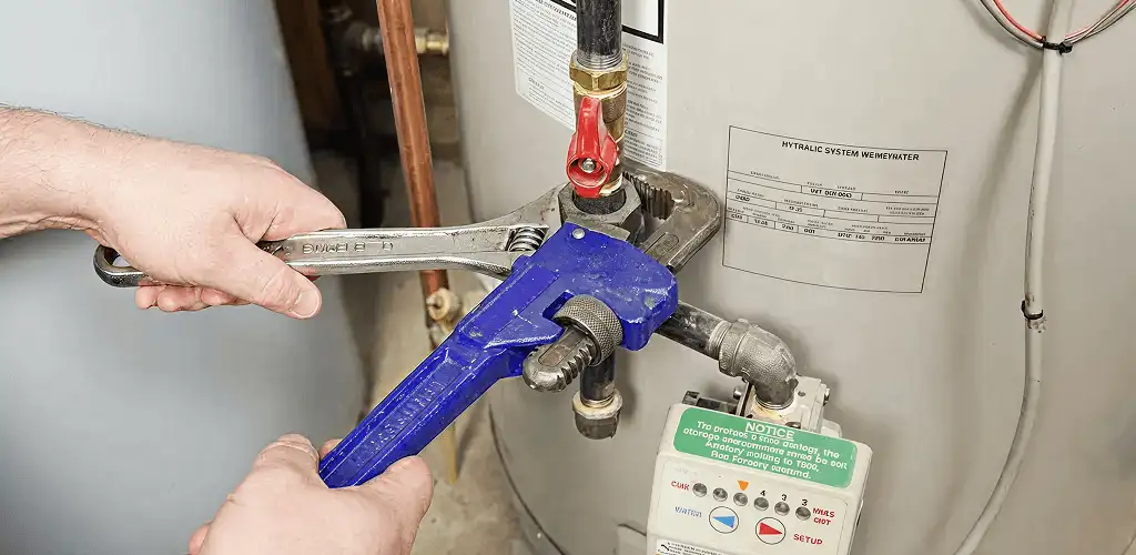 Water heater repair technician tightening the shutoff valve and supply line in Springfield, MO